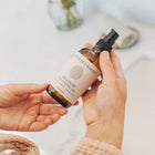 Hand holding a bottle of Meadow Cleansing Oil with a blurred background